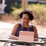 Black woman sitting at table with iPad