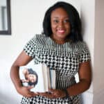 Black woman smiling and holding books