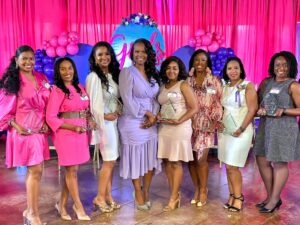 Eight Black women holding awards and smiling at Girls Ignited event. 
