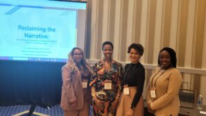 Photo of four smiling Black women after a conference presentation
