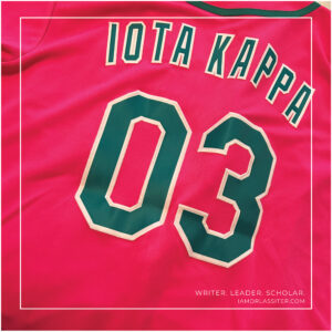 A pink jersey with green lettering spelling Iota Kappa 03